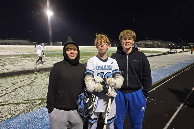 Drei Austauschschüler:innen abends am Sportplatz, eine Person in Lacrosse-Ausrüstung