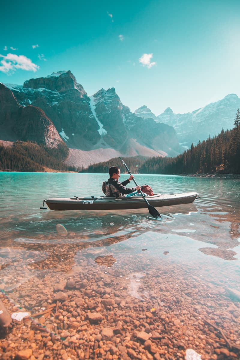 Kajakfahrer auf einem klaren Bergsee vor den schroffen Gipfeln der Rocky Mountains, Alberta
