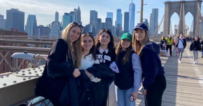 Fünf Austauschschülerinnen auf der Brooklyn Bridge vor der Skyline Manhattans
