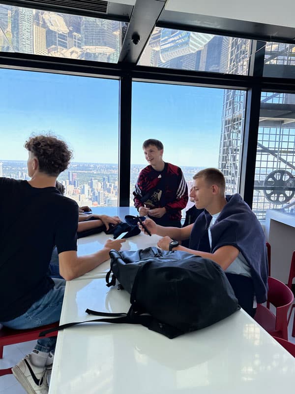 Austauschschüler:innen an einem Tisch in einem Hochhaus mit Blick über die Stadt