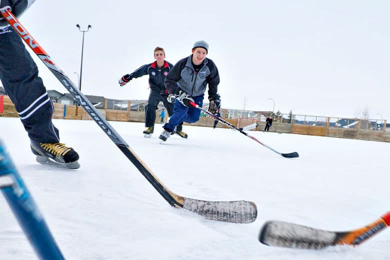 Austauschschüler:innen beim Eishockey auf einer Freiluft-Eisbahn in Alberta