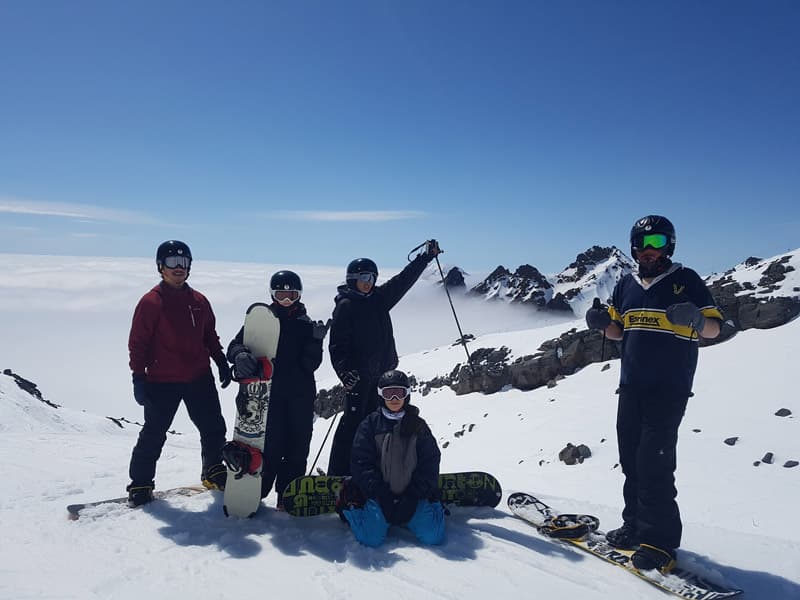 Snowboarder und Skifahrer auf einem verschneiten Berg über den Wolken in Neuseeland