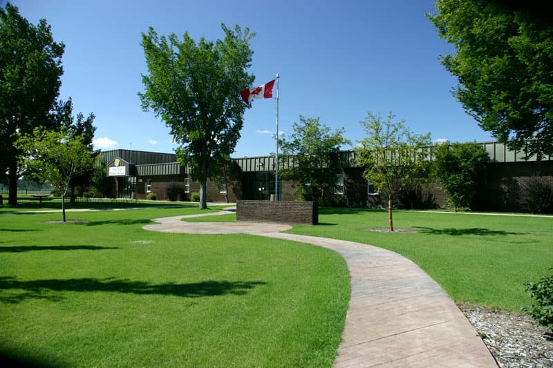 Flaches Schulgebäude mit kanadischer Flagge in Alberta – Schulalltag im Auslandsjahr