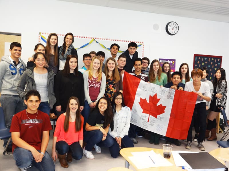 Internationale Austauschschüler:innen mit kanadischer Flagge im Klassenzimmer in Alberta