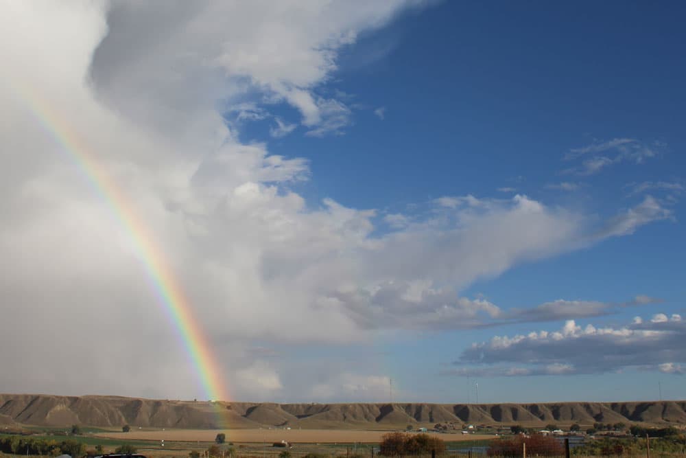 Regenbogen über der Prärie Albertas mit Hügelkette am Horizont
