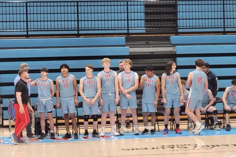 Basketballmannschaft einer High School in grauen Trikots stellt sich in der Sporthalle auf