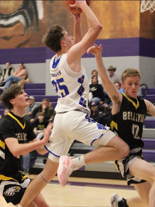 Basketballspieler im weißen Trikot springt zum Korbwurf, Gegner blocken – Schulsport in den USA