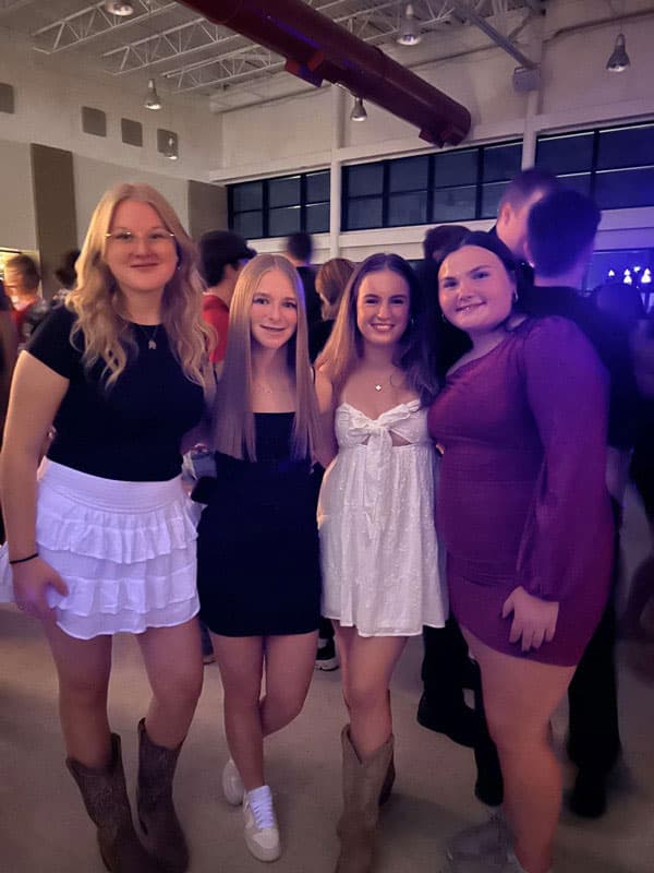 Vier Mädchen in festlichen Kleidern und Stiefeln beim Schulball ihrer High School in den USA