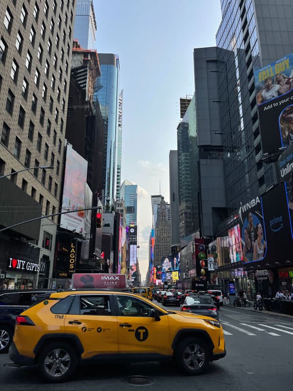 Gelbes Taxi vor Hochhäusern und Werbetafeln in Manhattan, New York