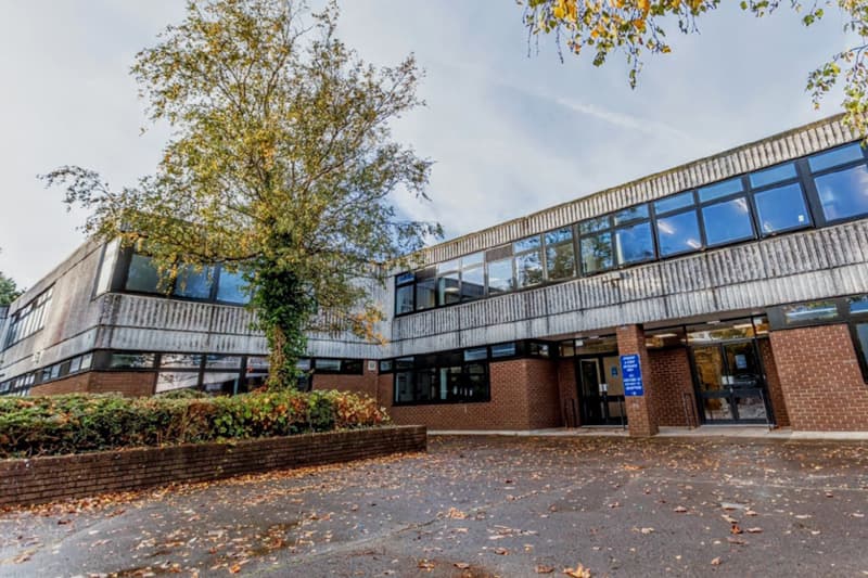 Modernes Schulgebäude mit großen Fensterbändern und Herbstbaum in Südwestengland
