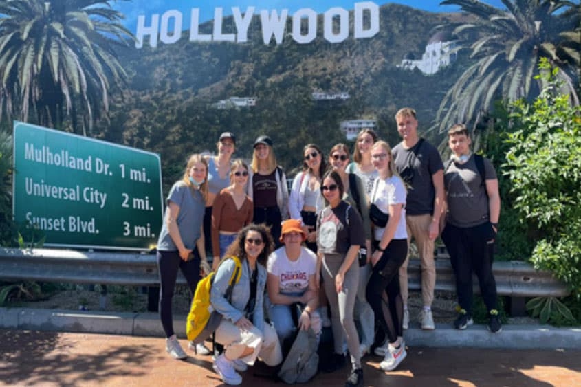 Teilnehmende vor dem Hollywood-Schriftzug und Straßenschild bei einer Reise nach Los Angeles