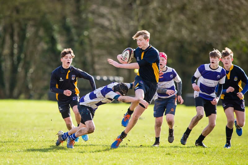 Schüler:innen beim Rugbyspiel auf einer Wiese – Schulsport in England