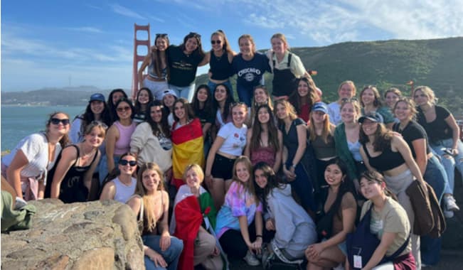 Große Gruppe von Austauschschüler:innen auf Felsen vor der Golden Gate Bridge in San Francisco