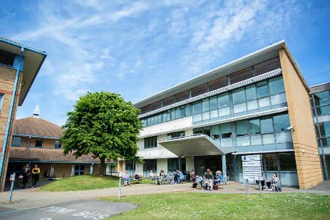 Modernes Schulgebäude mit großer Fensterfront und Baum auf dem Rasen in Südostengland